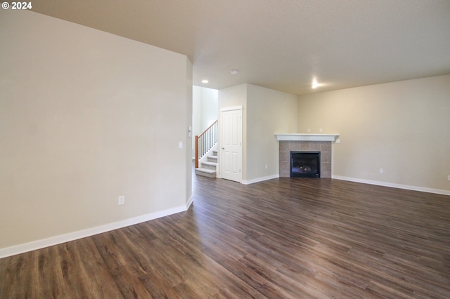 unfurnished living room featuring dark wood-type flooring and a tile fireplace