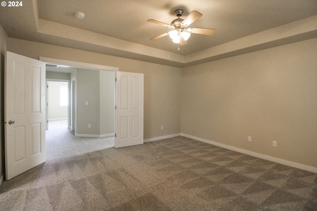 carpeted spare room with a tray ceiling, ceiling fan, and a textured ceiling