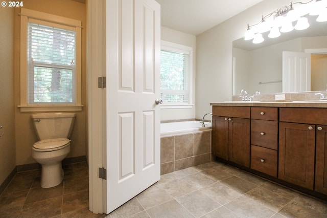 bathroom with tiled bath, toilet, and vanity