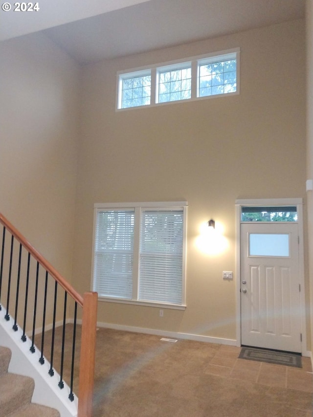 foyer entrance featuring a high ceiling and carpet floors