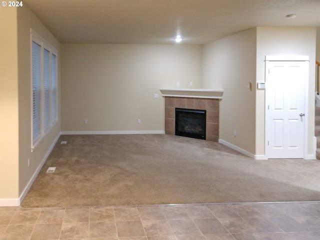 unfurnished living room featuring a tiled fireplace and light carpet