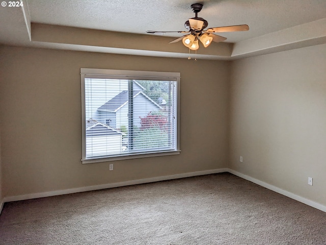 spare room with ceiling fan, a raised ceiling, carpet floors, and a textured ceiling