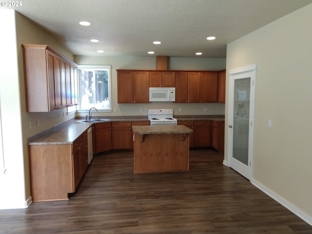 kitchen with sink, white appliances, a kitchen island, a textured ceiling, and dark hardwood / wood-style floors