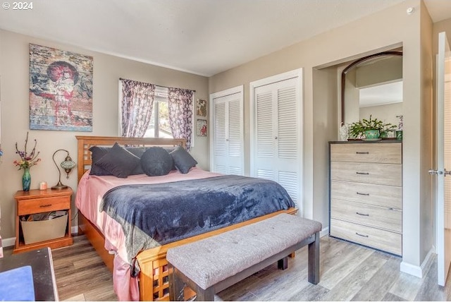 bedroom featuring light wood-type flooring, baseboards, and multiple closets