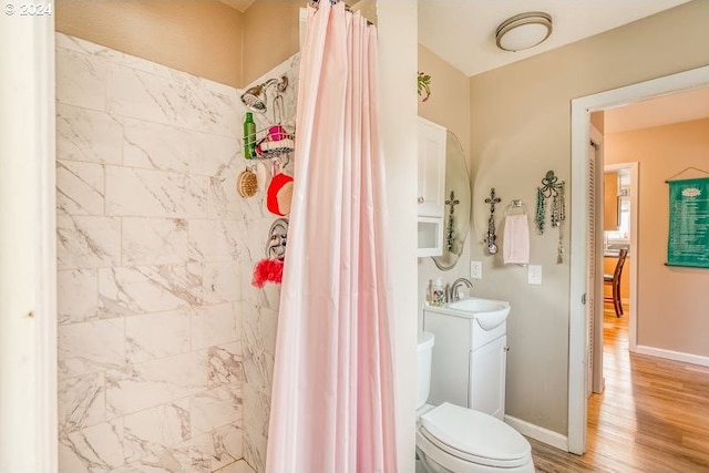 bathroom featuring toilet, a shower stall, vanity, wood finished floors, and baseboards