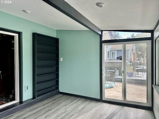 spare room with light wood-style flooring, baseboards, and a textured ceiling