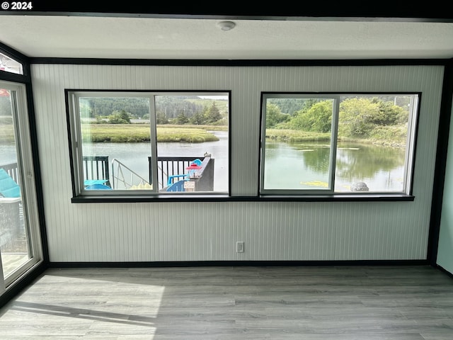 empty room with a water view, baseboards, and wood finished floors