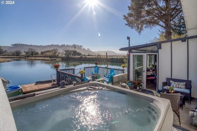 view of pool with a jacuzzi and a water and mountain view