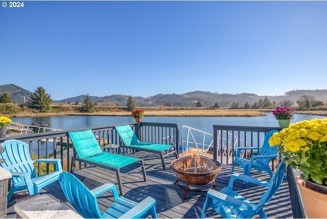 deck with an outdoor fire pit and a water and mountain view