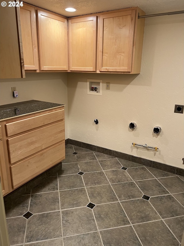 washroom with cabinets, washer hookup, hookup for an electric dryer, dark tile patterned floors, and gas dryer hookup