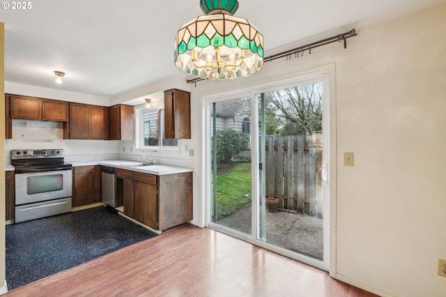 kitchen with sink, an inviting chandelier, light hardwood / wood-style floors, pendant lighting, and appliances with stainless steel finishes