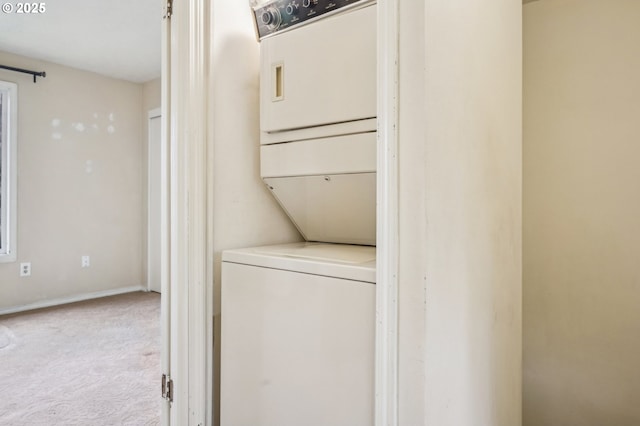 washroom featuring stacked washer / drying machine and light colored carpet