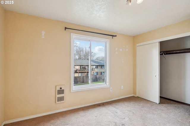 unfurnished bedroom featuring a closet, light carpet, and heating unit