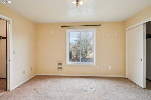 unfurnished bedroom with light colored carpet, a closet, and heating unit