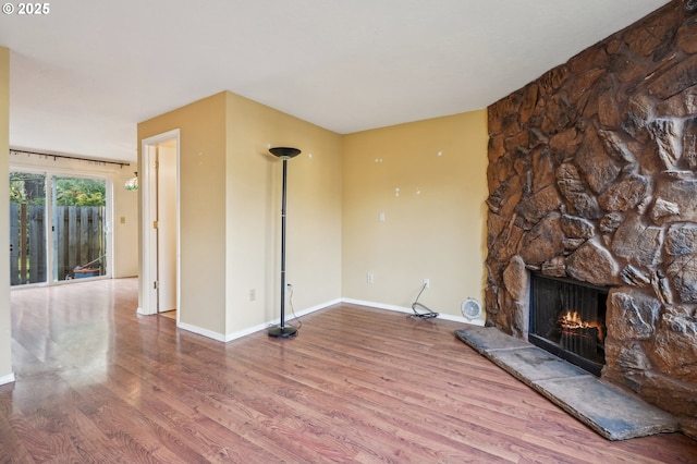 unfurnished living room featuring wood-type flooring and a stone fireplace