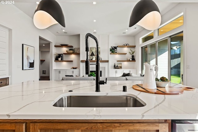 kitchen featuring light stone counters, dishwasher, and sink