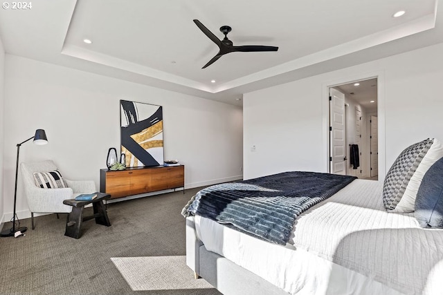 carpeted bedroom with a raised ceiling and ceiling fan