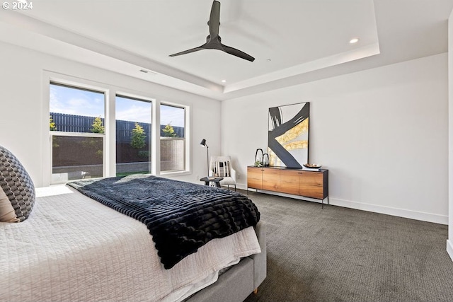 bedroom with ceiling fan, a raised ceiling, and dark carpet