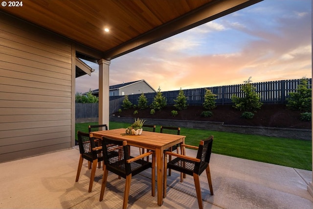 patio terrace at dusk featuring a lawn