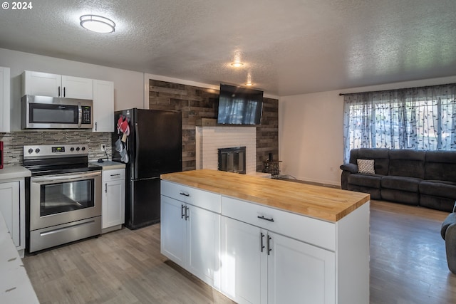 kitchen featuring white cabinets, a textured ceiling, stainless steel appliances, and wooden counters