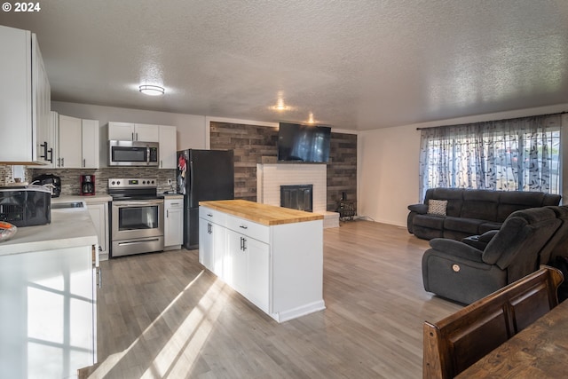 kitchen with decorative backsplash, appliances with stainless steel finishes, light hardwood / wood-style flooring, white cabinetry, and butcher block counters