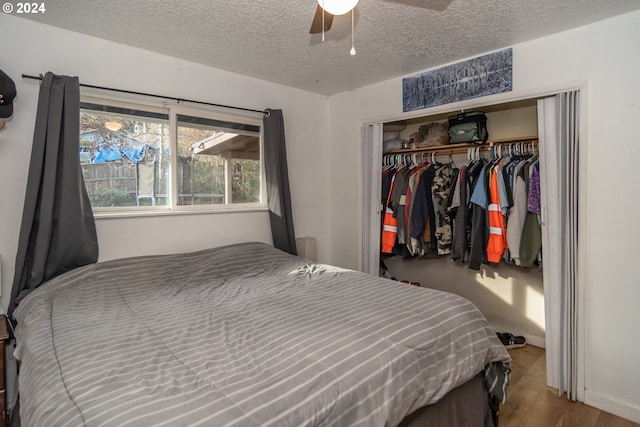 bedroom with ceiling fan, a closet, hardwood / wood-style floors, and a textured ceiling