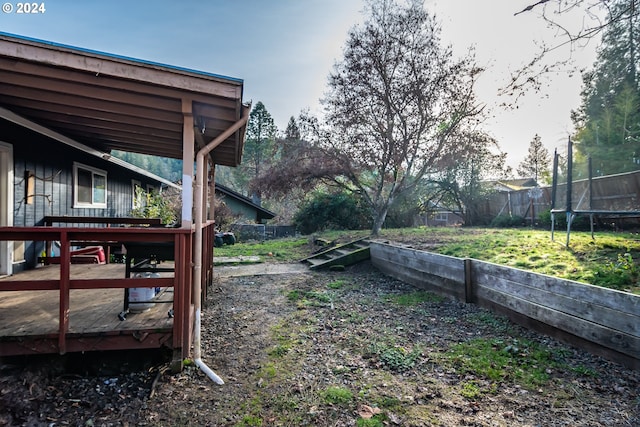 view of yard with a deck and a trampoline