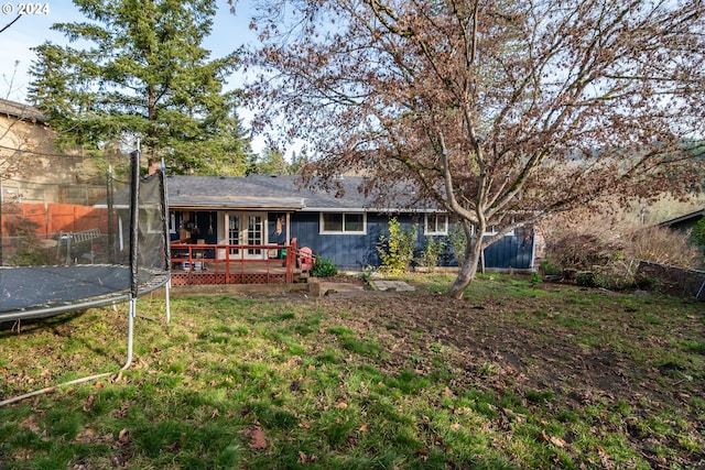 back of property featuring a deck and a trampoline