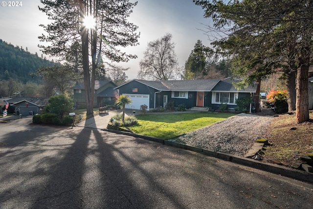 ranch-style home featuring a mountain view, a garage, and a front lawn