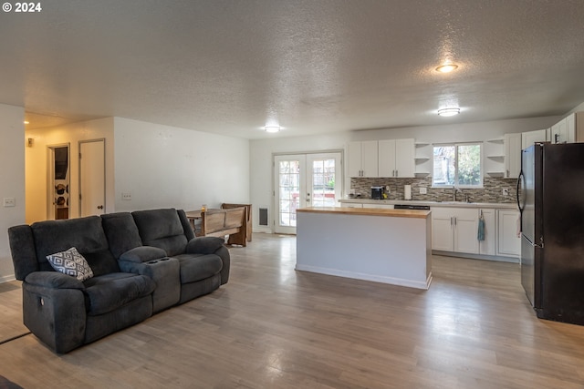 living room featuring a textured ceiling, light wood-type flooring, french doors, and sink