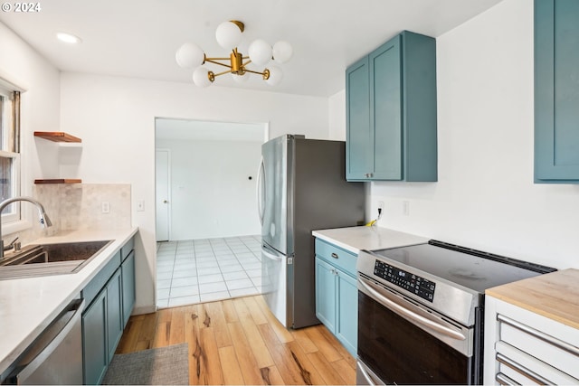 kitchen featuring sink, appliances with stainless steel finishes, an inviting chandelier, blue cabinetry, and light wood-type flooring