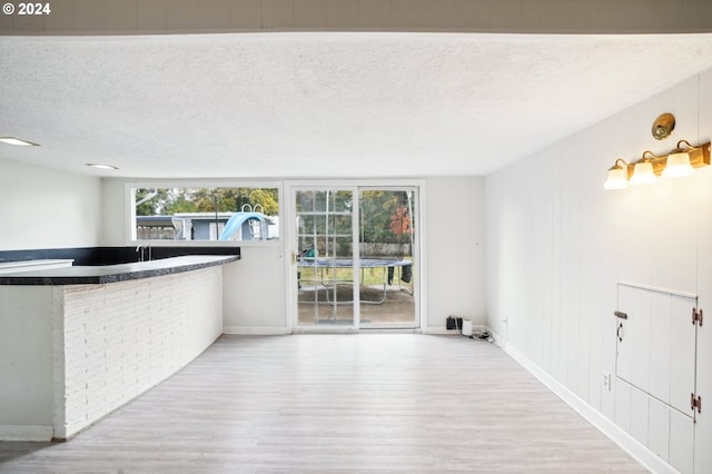 interior space featuring light hardwood / wood-style floors, a textured ceiling, and indoor bar