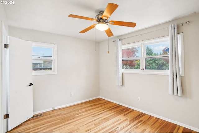 spare room featuring a wealth of natural light, ceiling fan, and light hardwood / wood-style flooring