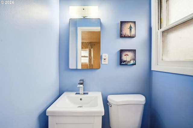 bathroom featuring toilet, a wealth of natural light, and sink