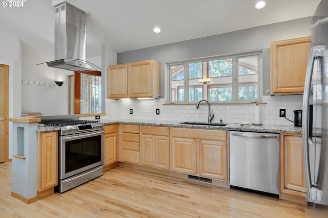 kitchen with light brown cabinets, light stone counters, island exhaust hood, stainless steel appliances, and a sink