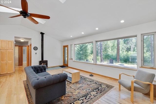 living area with plenty of natural light, ceiling fan, a wood stove, and vaulted ceiling