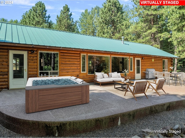 rear view of property featuring an outdoor living space, a hot tub, metal roof, outdoor dining area, and a patio area