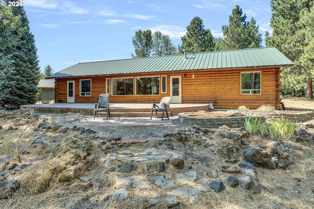 back of property featuring log siding, metal roof, and a patio