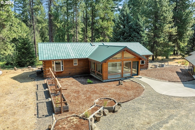 view of front of house featuring a standing seam roof, metal roof, a vegetable garden, and a sunroom