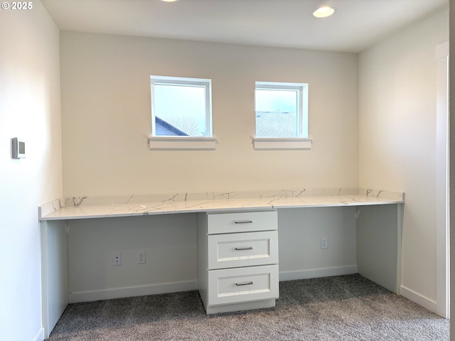 unfurnished office featuring built in desk and light carpet