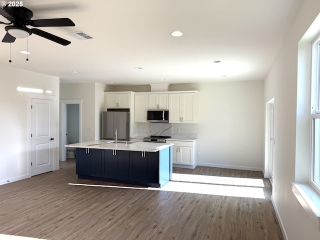 kitchen featuring white cabinets, a kitchen island with sink, appliances with stainless steel finishes, and light hardwood / wood-style flooring