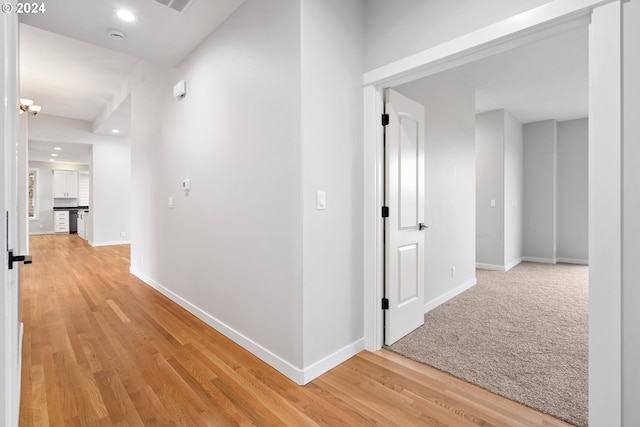 hallway with an inviting chandelier and light hardwood / wood-style flooring