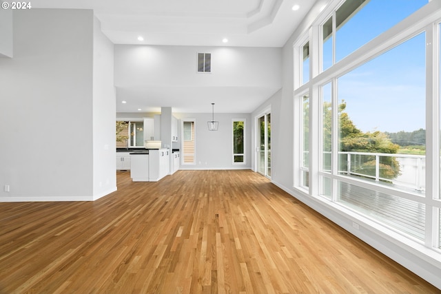 unfurnished living room featuring a high ceiling and light hardwood / wood-style floors