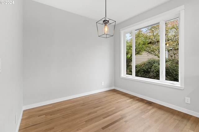 unfurnished dining area with an inviting chandelier and light hardwood / wood-style flooring