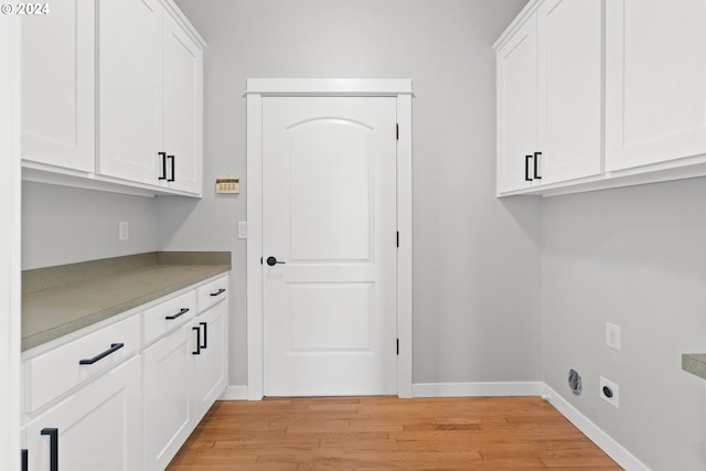 laundry area featuring cabinets, light hardwood / wood-style flooring, and electric dryer hookup