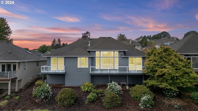 back house at dusk featuring a balcony