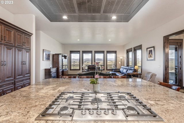 kitchen featuring a breakfast bar area, a tray ceiling, and light stone counters