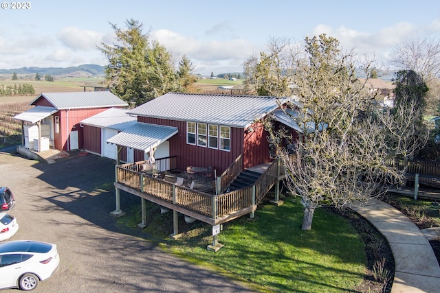 back of property with a deck with mountain view and a lawn