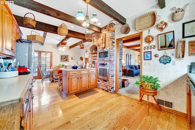 kitchen with appliances with stainless steel finishes, hanging light fixtures, light hardwood / wood-style floors, and beamed ceiling