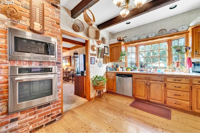 kitchen featuring sink, appliances with stainless steel finishes, an inviting chandelier, light hardwood / wood-style floors, and beam ceiling